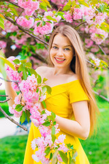 girl in a dress with bare shoulders holds a branch of a tree wit