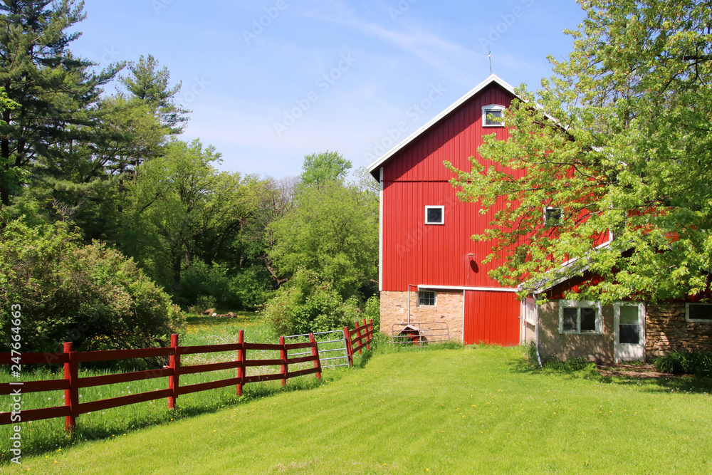 Wall mural beautiful spring landscape with red barn. scenic view with old style red barn between fresh green co