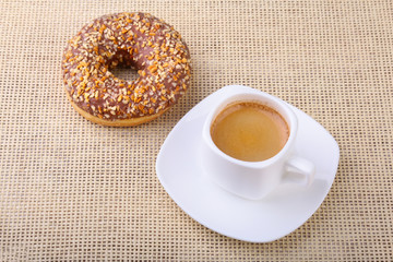 Coffee break with fresh donuts over textile background.