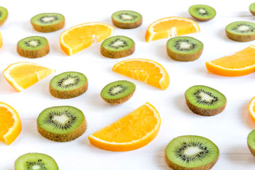 Fototapeta premium Pattern with oranges and kiwi slices on a white wooden background. The basis for the booklet, the background for the banner. Basis for design with tropical fruits