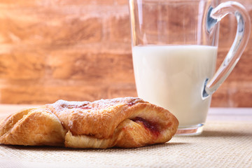 Breakfast with traditional hot cross bun with jam and glass with milk on wooden table. Top View