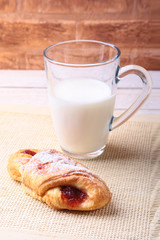 Breakfast with traditional hot cross bun with jam and glass with milk on wooden table. Top View