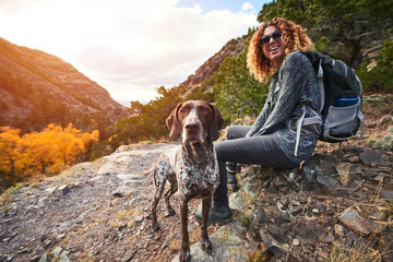 a young woman and her dog hiking to the top of a mountain