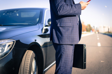 .a businessman standing near in front of.luxury car holding brief case or diplomat