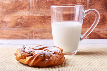 Chocolate and powdered sugar cream puff rings and glass with milk on wooden table. traditional Breakfast.