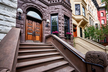 a row of brownstone buildings and stoops in an iconic neighborhood of Manhattan, New York City.