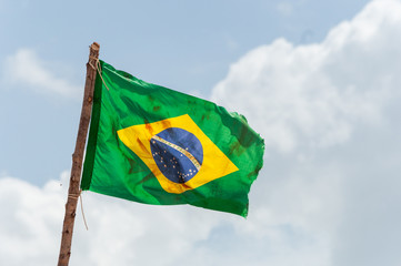 Brazilian flag is waving at a beautiful and peaceful blue sky at Amazonas river.