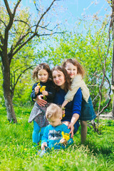 Fototapeta premium Mom with three children - boy and two girls smiling, and her children are hugging. Happy large family in nature.