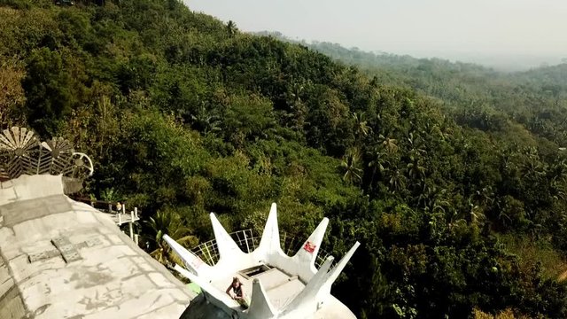 Drone rising next to chicken temple, Gereja Ajam in Java, Indonesia with a model in the crown.