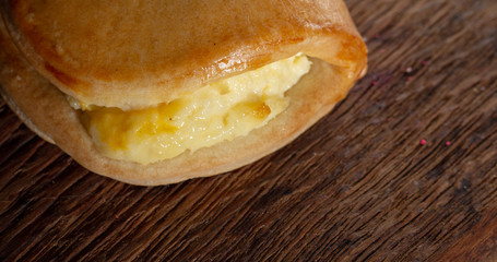 Sweet bun with cheese, juicy, on a brown oak background