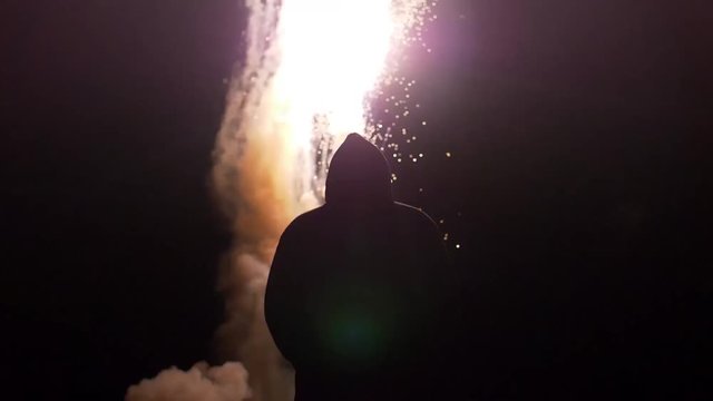 Conceptual shot of a silhouetted man standing in front of fireworks filmed in slow motion.