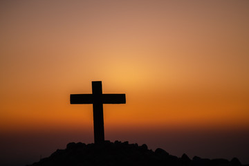 The silhouette of the cross across the mountain at sunset