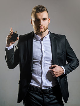 Male fragrance and perfumery, cosmetics. Man holding up bottle of perfumery. Cologne bottle.