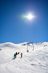 Fototapeta na wymiar T-Bar Lift in the Alps with sunshine and people