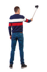 back view of standing young guy with smartphone in the hands of.