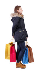 Side view of woman in winter jacket with shopping bags.