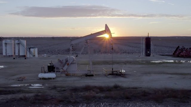 AERIAL: Oil pump jack with Incredible Texas sunset on farm field energy