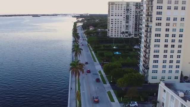 aerial drone shot of a bay drive aligned with palm trees as cars past in West Palm Beach Florida