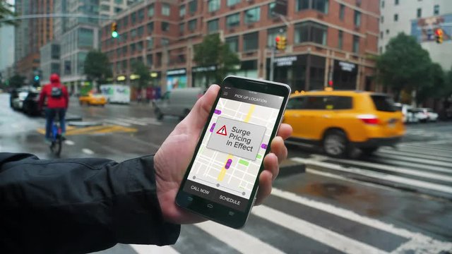A man uses a ride-sharing app on his cellular phone to call a driver and notices a surge pricing pop-up warning.	Shot at 60fps.  	