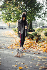 Young woman with puppy dog and coffee walking on street