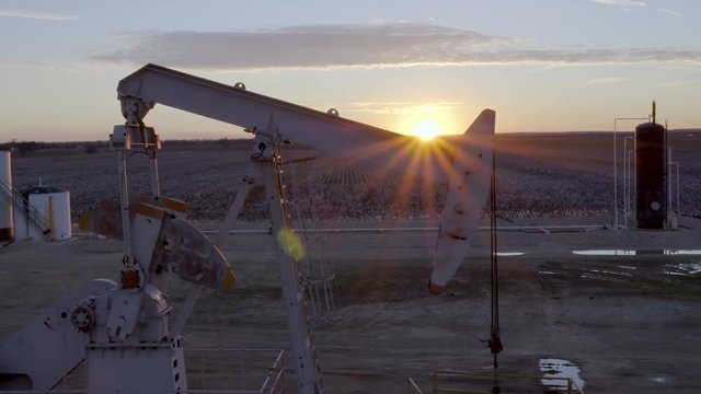AERIAL: Oil pump jack with Incredible Texas sunset on farm field energy