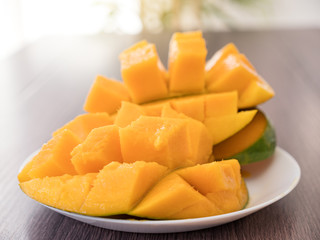 Half cutted cubes slices ripe mango on green palm leaf background