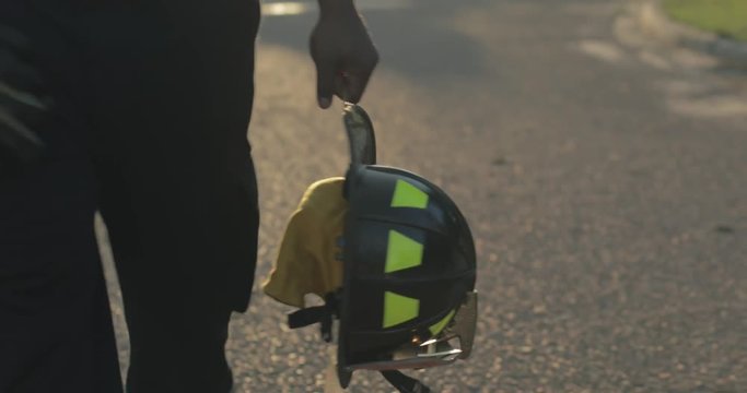 African American firefighter holding helmet