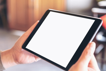 Mockup image of a woman holding black tablet pc with blank white screen horizontally while sitting in cafe