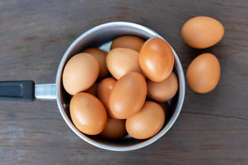 Fresh eggs are in a pot on a wood table.