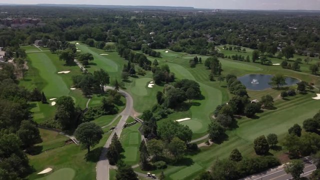 Aerial view of golf course, pull back reveal shot. Wide view of beautiful landscape and neighborhood