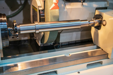 The metal shaft on the cylindrical grinding machine.The automotive part manufacturing process.