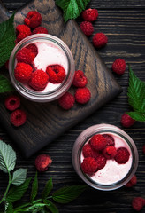 Raspberry smoothie in glass jars with fresh berry and yogurt on vintage wooden kitchen table background, flat lay, top view vertical image