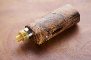 high end rebuildable dripping atomizer with stabilized wood regulated box mods on natural wood texture background, vaping device, selective focus