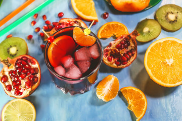 Pomegranate juice in a glass with pieces of ice on the background of cut citrus fruits.