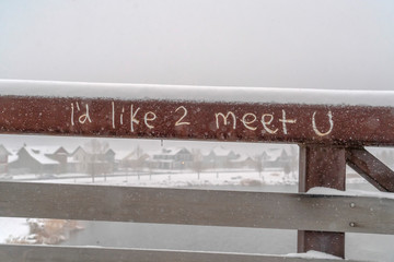 Graffiti scratched into metal railing of a bridge