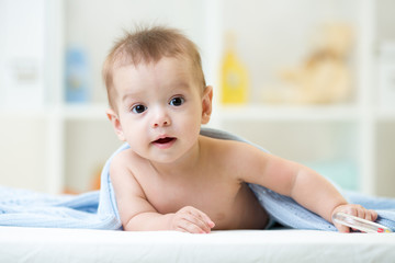 Adorable happy baby boy under towel indoor