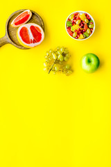 Healthy diet concept. Fruit salad near fresh fruits on yellow background top view space for text