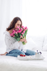 caucasian woman smelling tulips. good morning at Womans day. Breakfast on the bed