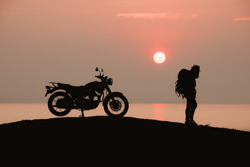 Silhouette of backpacker with Motorbike during sunrise or sunset,Beautiful sunset background, nature tourism concept