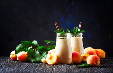 Healthy apricot smoothies with fresh fruits and flax seeds, in glass bottles, rustic kitchen table background, copy space, selective focus