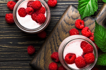 Raspberry smoothie in glass jars with fresh berry and yogurt on vintage wooden kitchen table background, flat lay, top view