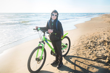 Fototapeta premium Boy rides a Bicycle along the sea on a sandy beach.