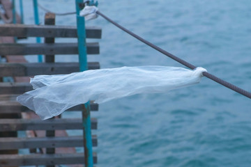 Plastic bag is tied to the cable of the sea pier.