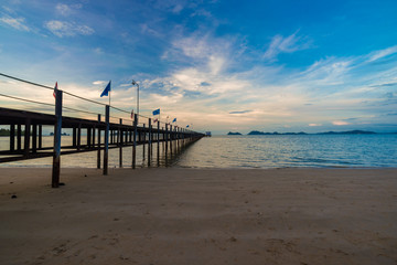 Obraz premium Poranny wschód słońca na plaży z mostem i chmurą kolorowe niebo