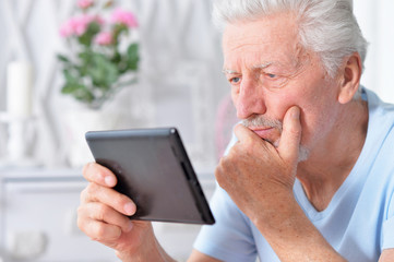 Portrait of senior man using tablet at home