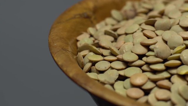 Lentils. Rotation. Close up. Heap of raw uncooked brown lentils in a bowl in rotation.  Food background.  gray background, studio shot. Healthy organic food diet concept