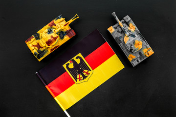 War, military threat, military power concept. Germany. Tanks toy near German flag on black...