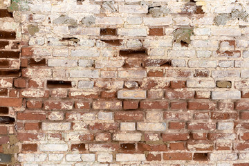 a fragment of an old flaked unrestored brick wall of an orthodoxal church in a small Russian town