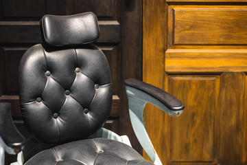 A leather chair with armrest in front of wood panel
