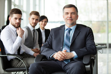 Mature smiling business manager in front of his business team